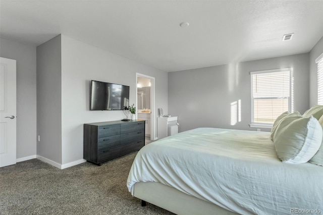 bedroom featuring dark colored carpet, visible vents, ensuite bath, and baseboards