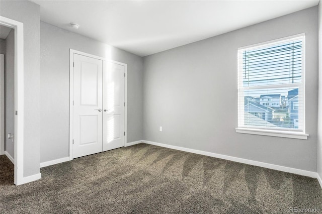 unfurnished bedroom featuring dark carpet and a closet