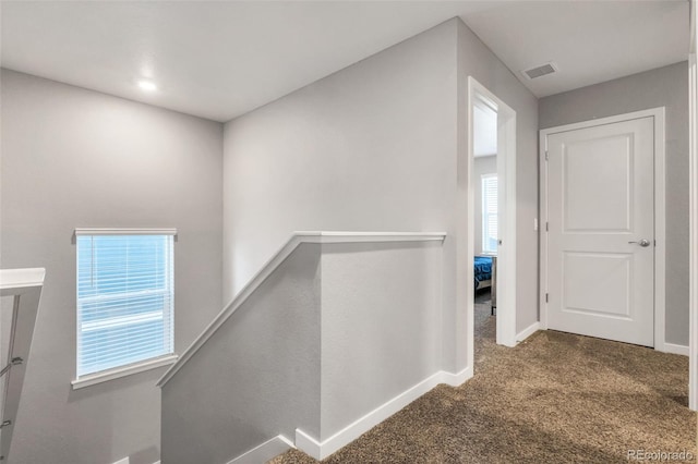 corridor with baseboards, visible vents, carpet flooring, and an upstairs landing