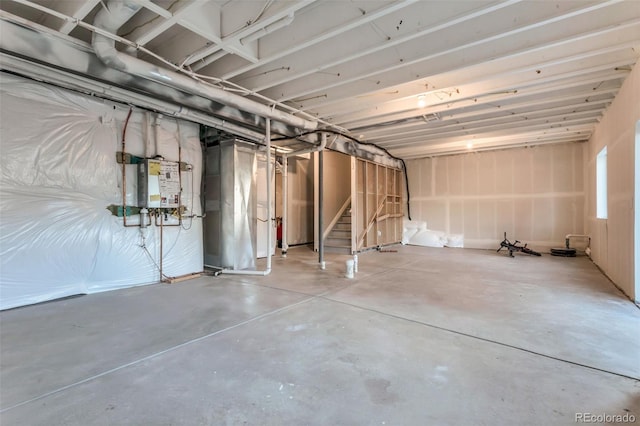 unfinished below grade area featuring tankless water heater and stairs