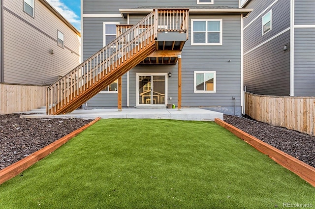 rear view of house with a yard, a fenced backyard, a patio, and stairs