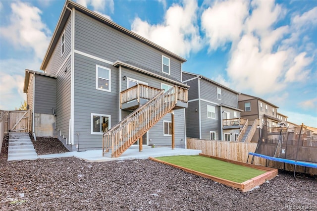 rear view of property with a trampoline and a patio