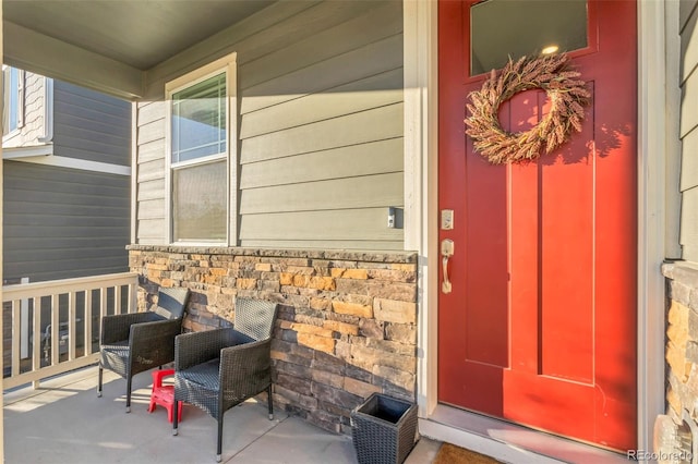 entrance to property featuring a porch and stone siding