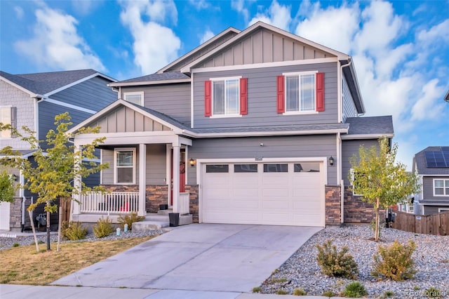 craftsman house featuring board and batten siding, stone siding, a porch, and concrete driveway