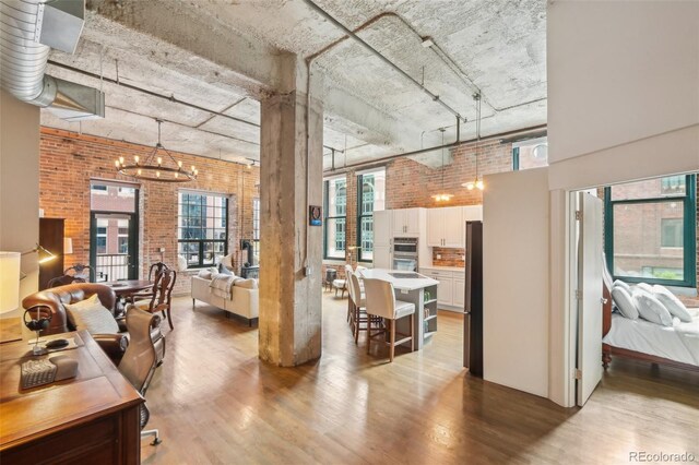 1801 Wynkoop St Unit 208, Denver, CO 80202 - interior space with wood finished floors, brick wall, a towering ceiling, and a chandelier