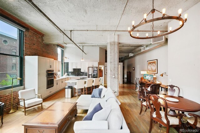1801 Wynkoop St Unit 208, Denver, CO 80202 - living area featuring a chandelier, light wood-style flooring, a high ceiling, and brick wall
