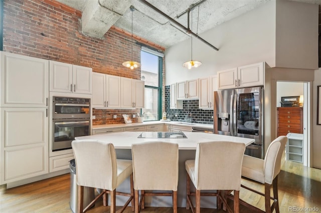 1801 Wynkoop St Unit 208, Denver, CO 80202 - kitchen featuring a high ceiling, appliances with stainless steel finishes, backsplash, light wood-style flooring, and a breakfast bar