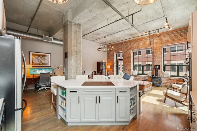 1801 Wynkoop St Unit 208, Denver, CO 80202 - kitchen featuring freestanding refrigerator, a wood stove, open shelves, wood finished floors, and brick wall