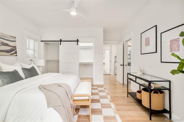 bedroom featuring light hardwood / wood-style floors, a barn door, and ceiling fan