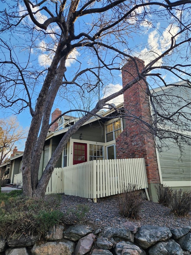 view of front of house with a chimney and fence