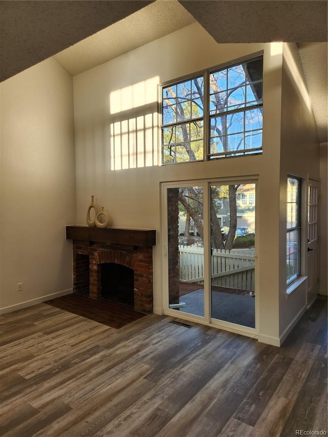 unfurnished living room with wood finished floors, baseboards, and a towering ceiling