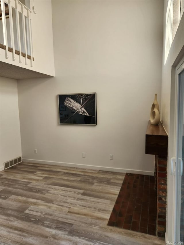 unfurnished living room featuring visible vents, baseboards, a high ceiling, and wood finished floors