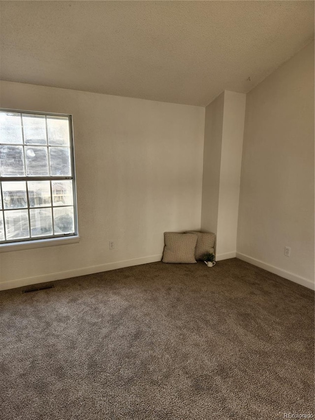 carpeted empty room with baseboards and a textured ceiling