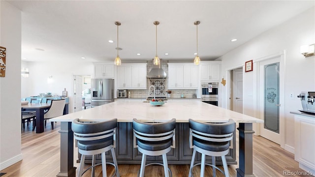1246 Highland Pl, Erie, CO 80516 - kitchen with stainless steel appliances, wall chimney range hood, backsplash, white cabinetry, and light wood-style floors