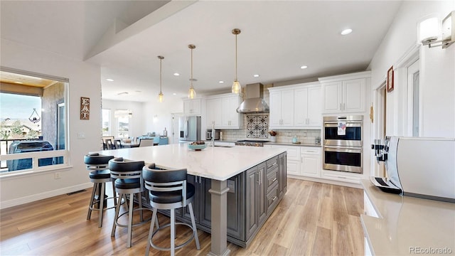 1246 Highland Pl, Erie, CO 80516 - kitchen featuring stainless steel appliances, wall chimney exhaust hood, gray cabinets, white cabinetry, and light wood finished floors