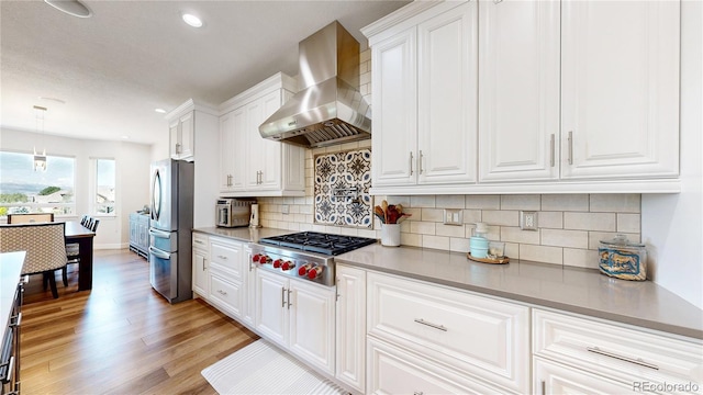 1246 Highland Pl, Erie, CO 80516 - kitchen with wall chimney range hood, appliances with stainless steel finishes, light wood-type flooring, white cabinetry, and recessed lighting
