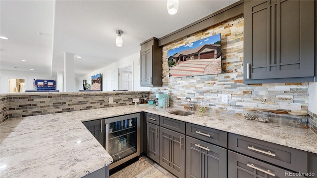 1246 Highland Pl, Erie, CO 80516 - kitchen with beverage cooler, light stone countertops, tasteful backsplash, a peninsula, and gray cabinets