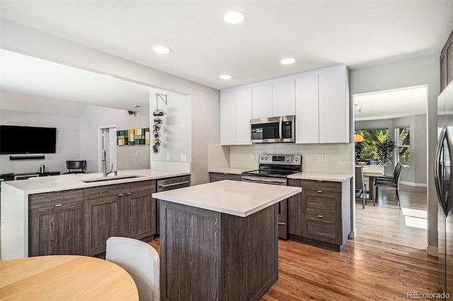 9673 Pinebrook St, Highlands Ranch, CO 80130 - kitchen featuring stainless steel appliances, a sink, light wood finished floors, light countertops, and white cabinets
