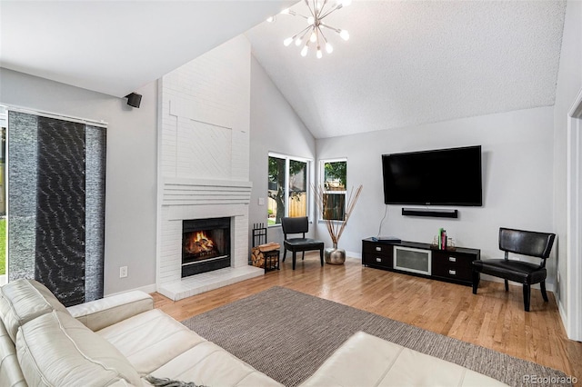 9673 Pinebrook St, Highlands Ranch, CO 80130 - living area featuring a chandelier, wood finished floors, a brick fireplace, baseboards, and high vaulted ceiling
