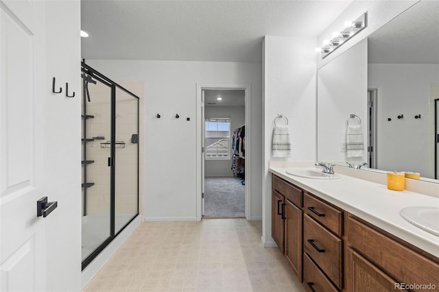 1228 Argali Dr, Severance, CO 80550 - full bath featuring a shower stall, double vanity, a walk in closet, a textured ceiling, and baseboards
