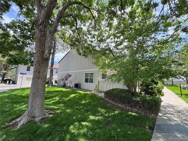 971 S Evanston Cir, Aurora, CO 80012 - view of home's exterior with board and batten siding, a lawn, and central AC unit