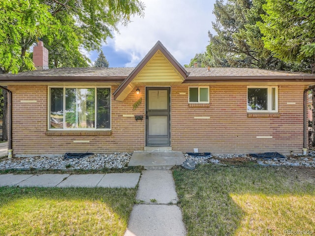 1455 S Zephyr St, Lakewood, CO 80232 - view of front of house with brick siding, a front yard, a chimney, and a shingled roof