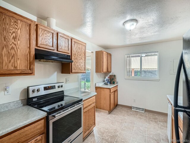 1455 S Zephyr St, Lakewood, CO 80232 - kitchen featuring electric stove, under cabinet range hood, light countertops, brown cabinets, and a textured ceiling