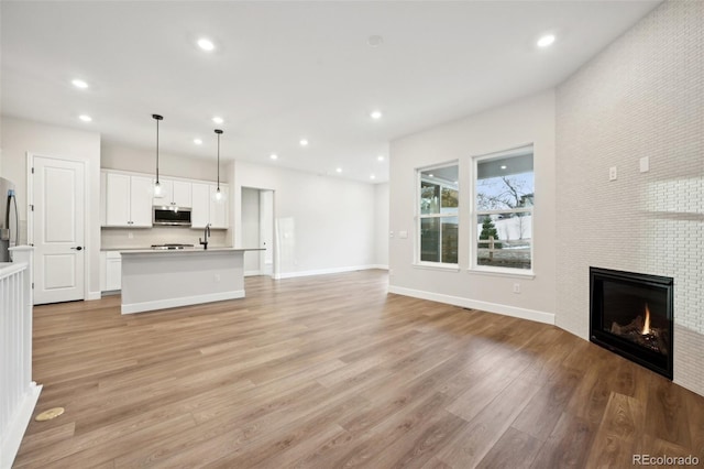 unfurnished living room featuring light hardwood / wood-style flooring and a tiled fireplace