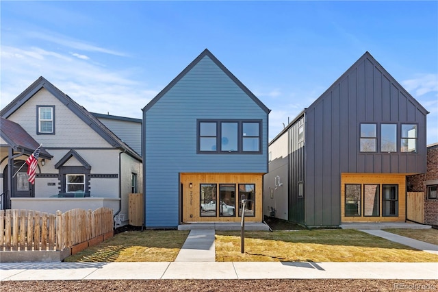 exterior space featuring board and batten siding, fence, and a front lawn