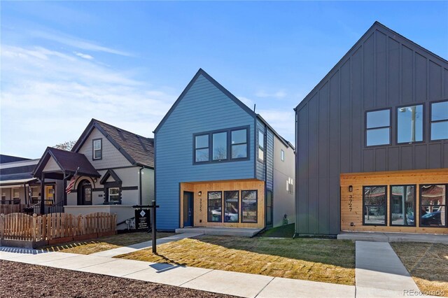 view of front of house featuring fence, a front lawn, and board and batten siding