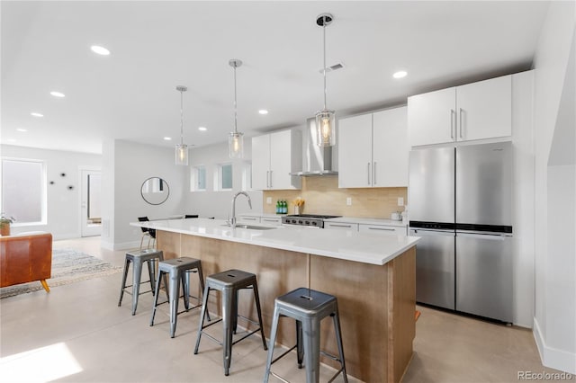 3725 N Franklin St, Denver, CO 80205 - kitchen featuring a kitchen bar, a sink, freestanding refrigerator, a kitchen island with sink, and wall chimney range hood