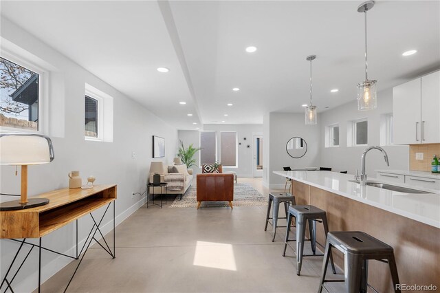 3725 N Franklin St, Denver, CO 80205 - kitchen featuring recessed lighting, baseboards, a sink, white cabinetry, and a kitchen breakfast bar