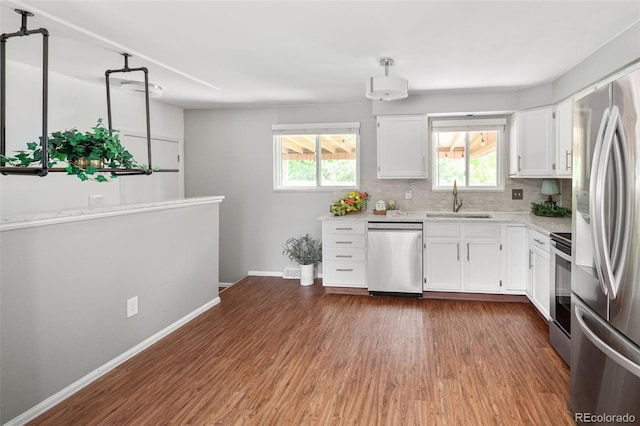 6353 W 78th Ave, Arvada, CO 80003 - kitchen with appliances with stainless steel finishes, wood finished floors, white cabinetry, and healthy amount of natural light