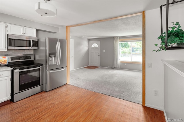 6353 W 78th Ave, Arvada, CO 80003 - kitchen featuring appliances with stainless steel finishes, white cabinets, light wood-style floors, light countertops, and open floor plan