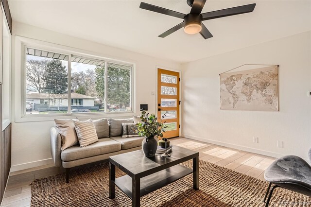 living room featuring a healthy amount of sunlight, baseboards, ceiling fan, and light wood-type flooring