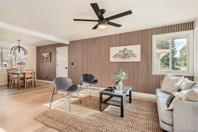 living area with beamed ceiling, a ceiling fan, baseboards, and light wood finished floors