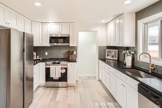kitchen featuring a sink, white cabinetry, dark countertops, and stainless steel appliances