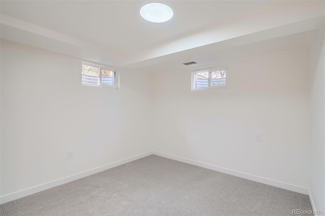 basement with baseboards, a healthy amount of sunlight, and light carpet