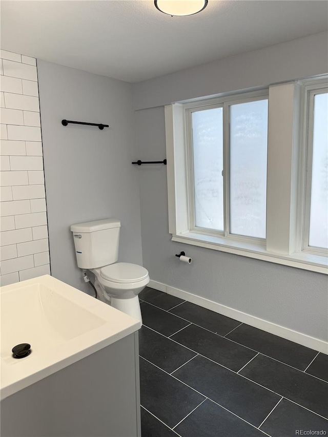 full bathroom featuring plenty of natural light, tile patterned flooring, toilet, and baseboards