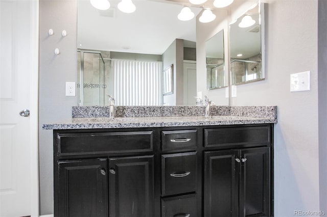 bathroom featuring a sink, a stall shower, and double vanity