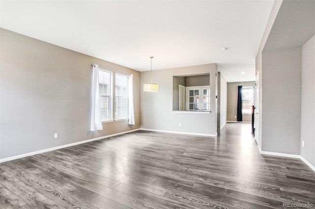unfurnished living room with baseboards and dark wood-type flooring
