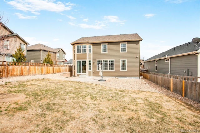 rear view of house featuring a fenced backyard and a lawn