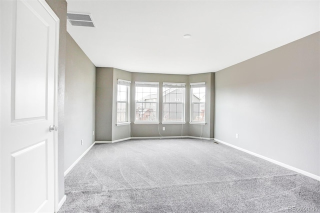 carpeted spare room with visible vents and baseboards