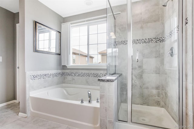 bathroom with a garden tub, baseboards, a stall shower, and a wealth of natural light