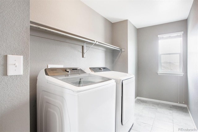 laundry room featuring separate washer and dryer, a textured wall, laundry area, and baseboards