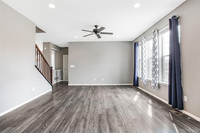 unfurnished living room with ceiling fan, visible vents, wood finished floors, stairway, and baseboards
