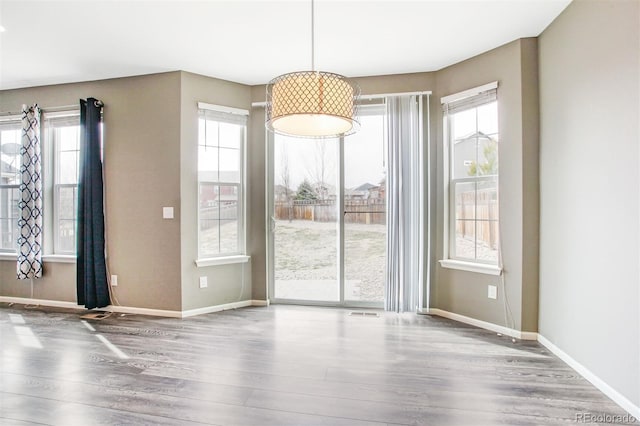 unfurnished dining area featuring baseboards and wood finished floors