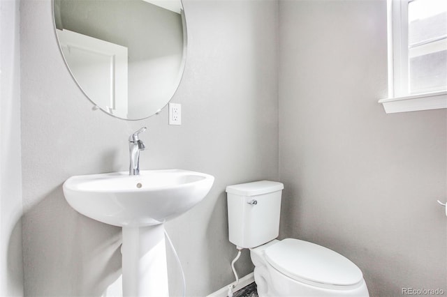 half bath with baseboards and toilet