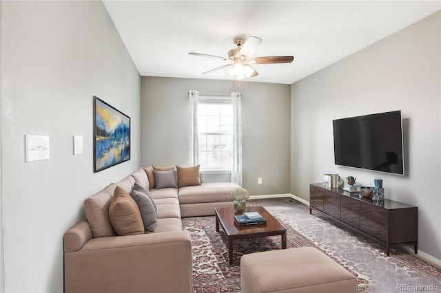 living area with baseboards, a ceiling fan, and carpet flooring