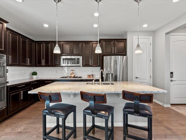 5439 Verbena St, Denver, CO 80238 - kitchen with stainless steel appliances, a sink, decorative backsplash, a kitchen breakfast bar, and recessed lighting
